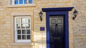 Un bâtiment en pierre avec une porte bleu foncé, une fenêtre et deux lanternes fixées au mur.
