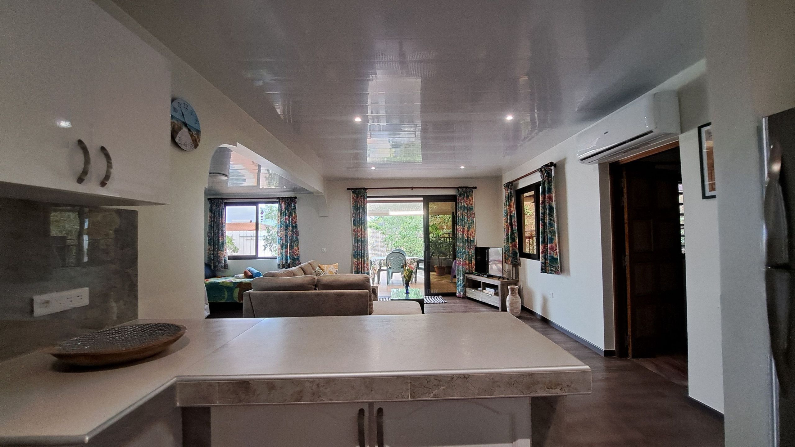 A modern kitchen with a large island, a dining area with a sofa, and a view of the outdoors.