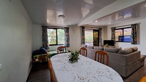 A living room with a dining table, sofas, a TV, and a ceiling light.