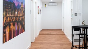 A hallway with wooden flooring, white walls, and a large cityscape painting on the left. There is a table with chairs on the right. - ROMA MIA IN TRASTEVERE (Rome)