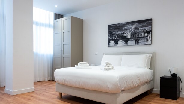A modern bedroom with a large bed, a nightstand, and a wall-mounted artwork of a cityscape. - ROMA MIA IN TRASTEVERE (Rome)
