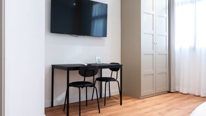 A room with a flat-screen TV mounted on the wall, a desk with two chairs, and a wardrobe. - ROMA MIA IN TRASTEVERE (Rome)