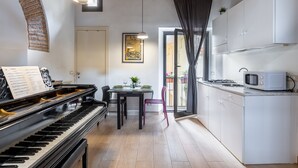 A modern kitchen with a built-in microwave, a dining area with a piano, and a view through a glass door.