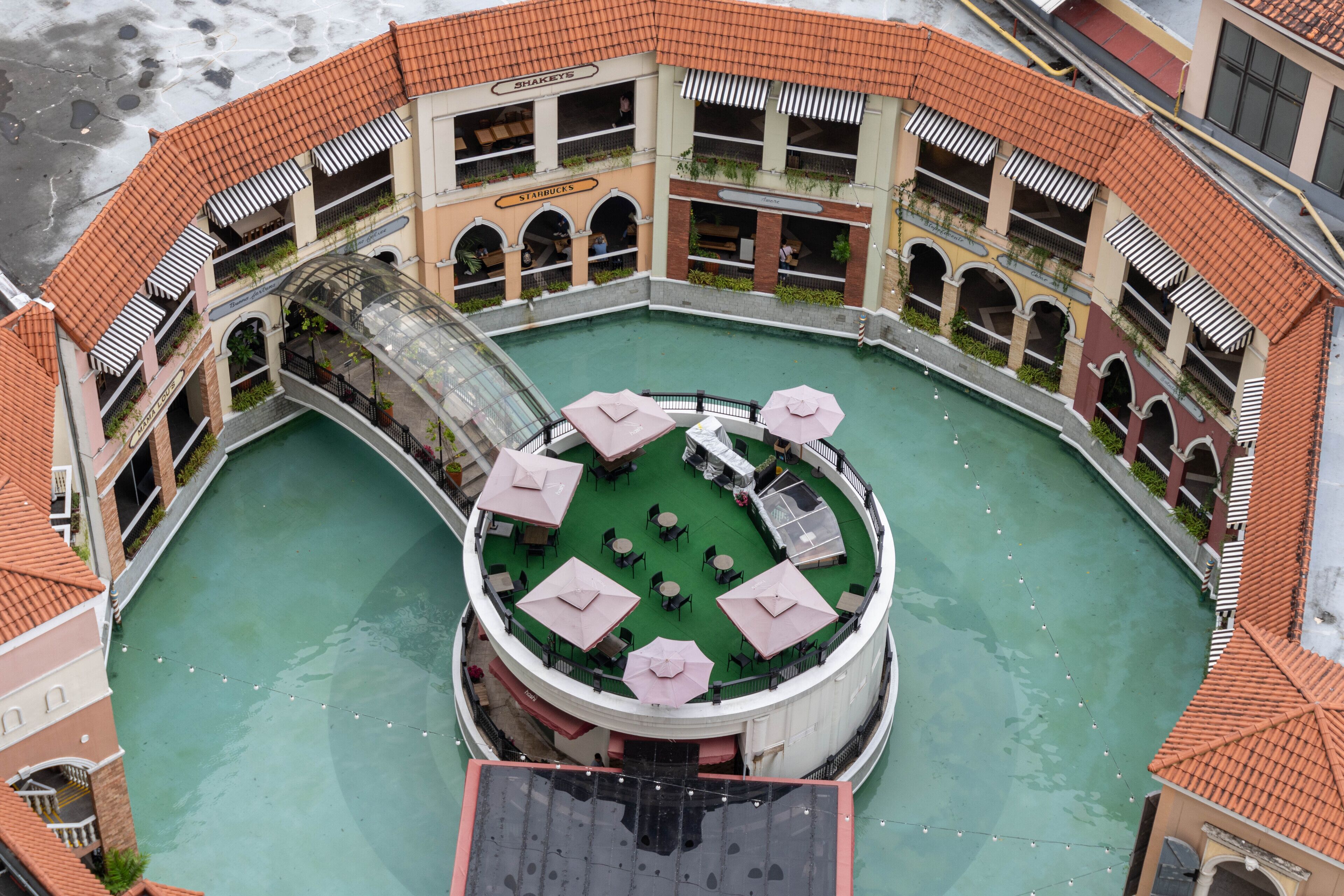 A circular courtyard with a central pool, surrounded by multiple floors of a building with balconies and outdoor seating areas.