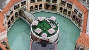 Ein kreisförmiger Innenhof mit einem zentralen Pool, umgeben von mehreren Stockwerken eines Gebäudes mit Balkonen und Außenbereichen zum Sitzen.