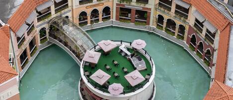 A circular courtyard with a central pool, surrounded by multiple floors of a building with balconies and outdoor seating areas.