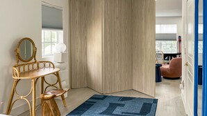 Ein Schlafzimmer mit einem Holzschrank, einem Schminktisch mit Spiegel, einem Bett und einem blauen Teppich.
