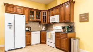 Una cocina con armarios de madera, un refrigerador, un microondas, un lavavajillas y una estufa.