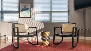 Una sala moderna con dos sillones mecedores negros, un tapete rojo con textura y una pieza decorativa única en dorado y plateado.