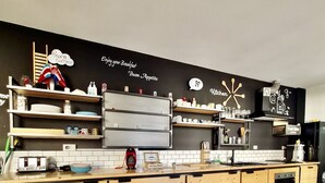 Moderni keittiö, jossa on puukuvioiset kaapit, musta välitila ja erilaisia keittiölaitteita.