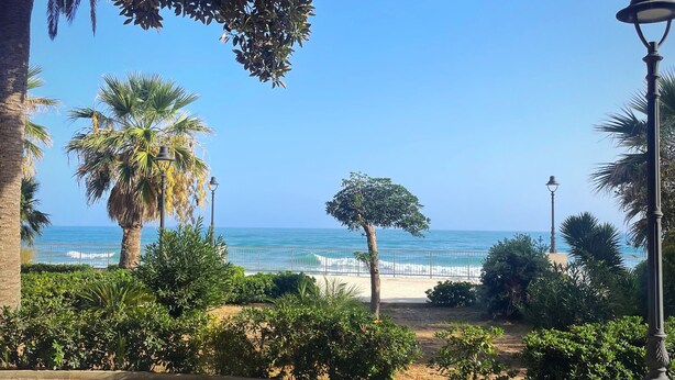 Ein gepflasterter Weg mit Blick auf den Strand und das Meer.