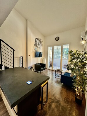 A modern living space with a kitchen area, a dining table, a sofa, and a large potted plant. - BALCON CELESTES 32 (Firenze)