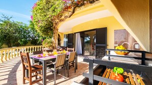 An outdoor dining area with a table set for two, chairs, a grill, and a view of the garden. - Peaceful villa with pool & BBQ (Albufeira)