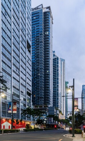 A modern urban street with high-rise buildings, street lamps, and a clear sky. - Luxury 2BR Gem in One Uptown, bgc (Taguig)