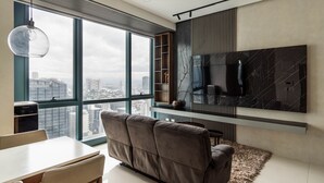 Uma sala de estar moderna com uma janela grande, um sofá, uma TV na parede e uma mesa pequena.
