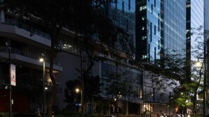 Um edifício moderno de grande porte com janelas de vidro refletivas e uma rua na frente.