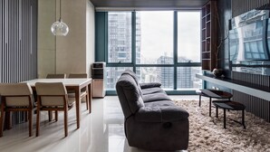 Uma sala de estar moderna com sofá, mesa de jantar, cadeiras e uma grande janela com vista para a cidade.