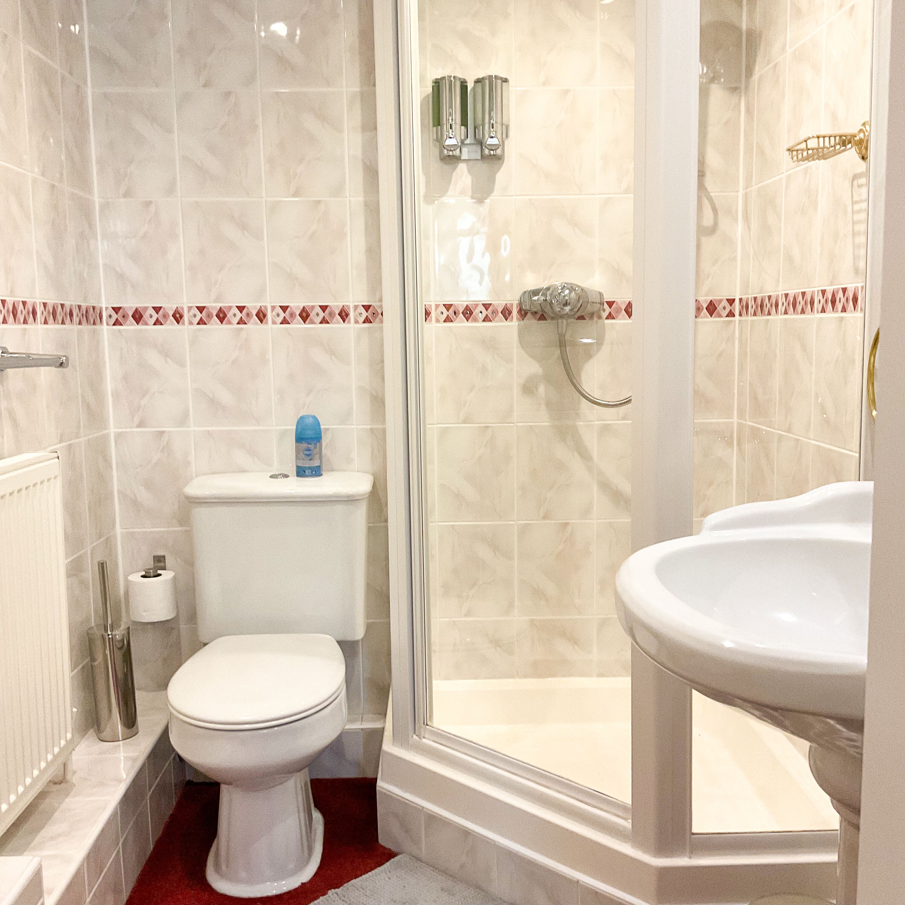 A bathroom with a toilet, a shower, and a sink.