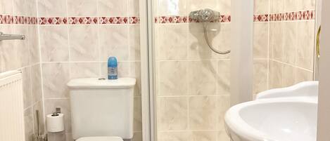 A bathroom with a toilet, a shower, and a sink.