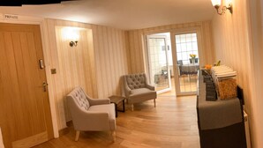 A hotel room with a wooden door labeled "PRIVATE," a seating area with two armchairs, a small table, and a sofa. - Southlands B&B (Cheltenham)
