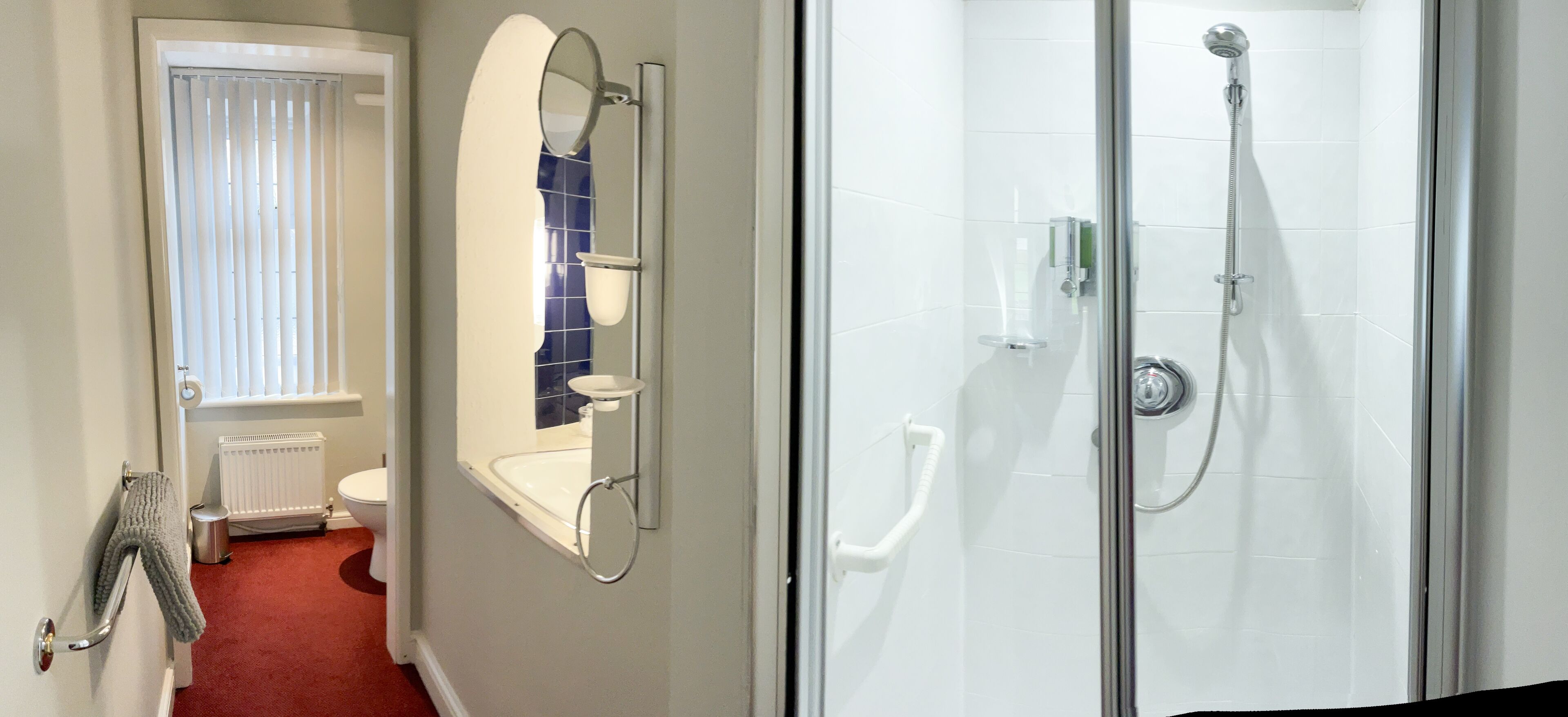 A bathroom with a toilet, a sink, a mirror, and a shower area.