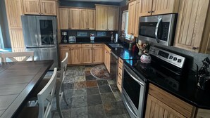 Une cuisine moderne avec des meubles en bois, des appareils en acier inoxydable et un plan de travail noir.