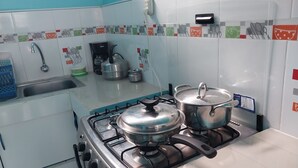 A kitchen with a gas stove, two pots, a coffee maker, and a sink.