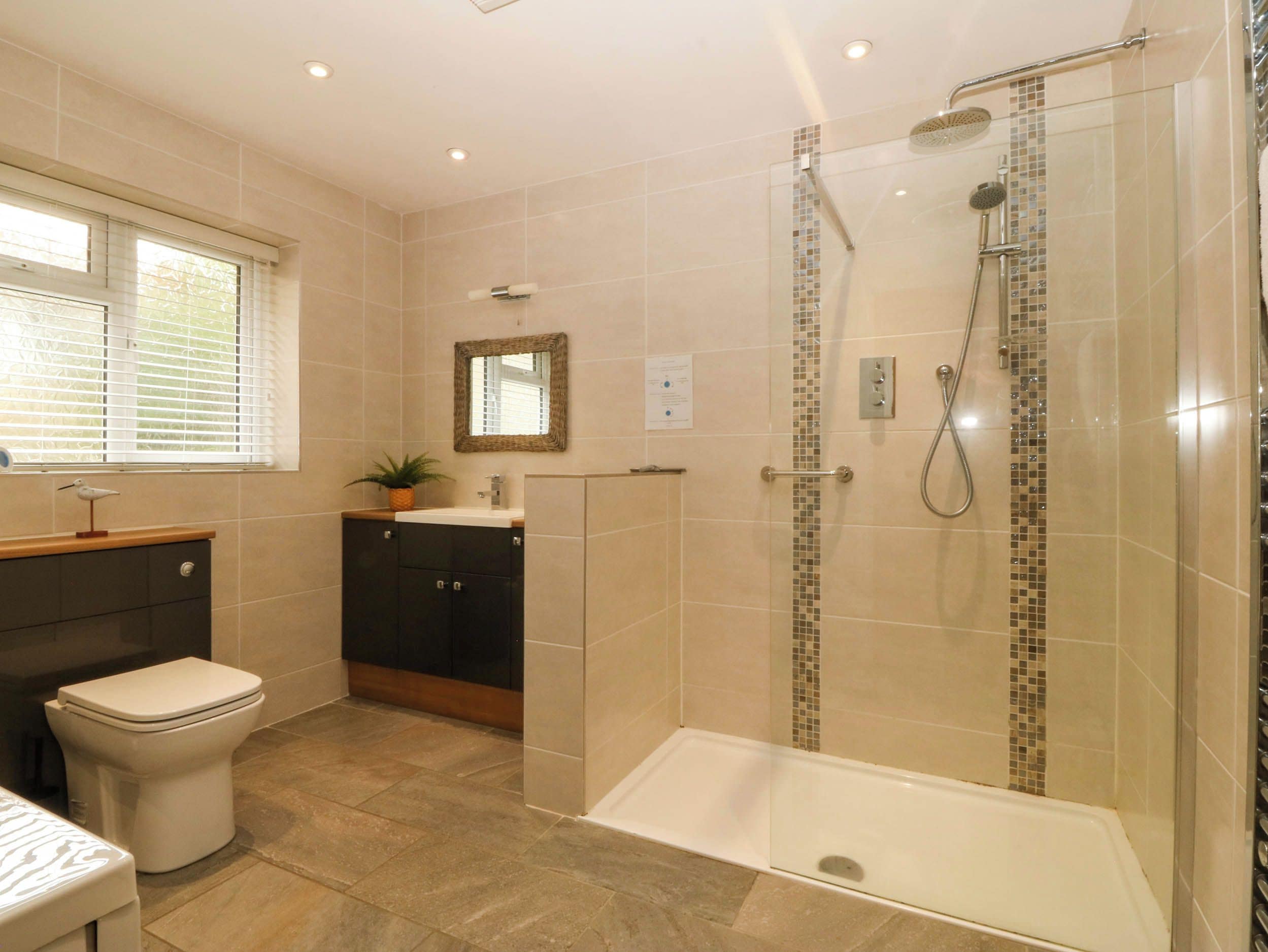 Une salle de bain comprenant des toilettes, un lavabo, un miroir, une douche et une baignoire.