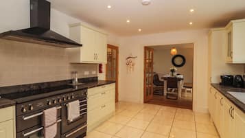A kitchen with a stove, oven, and cabinets. There is a dining area with a table and chairs.