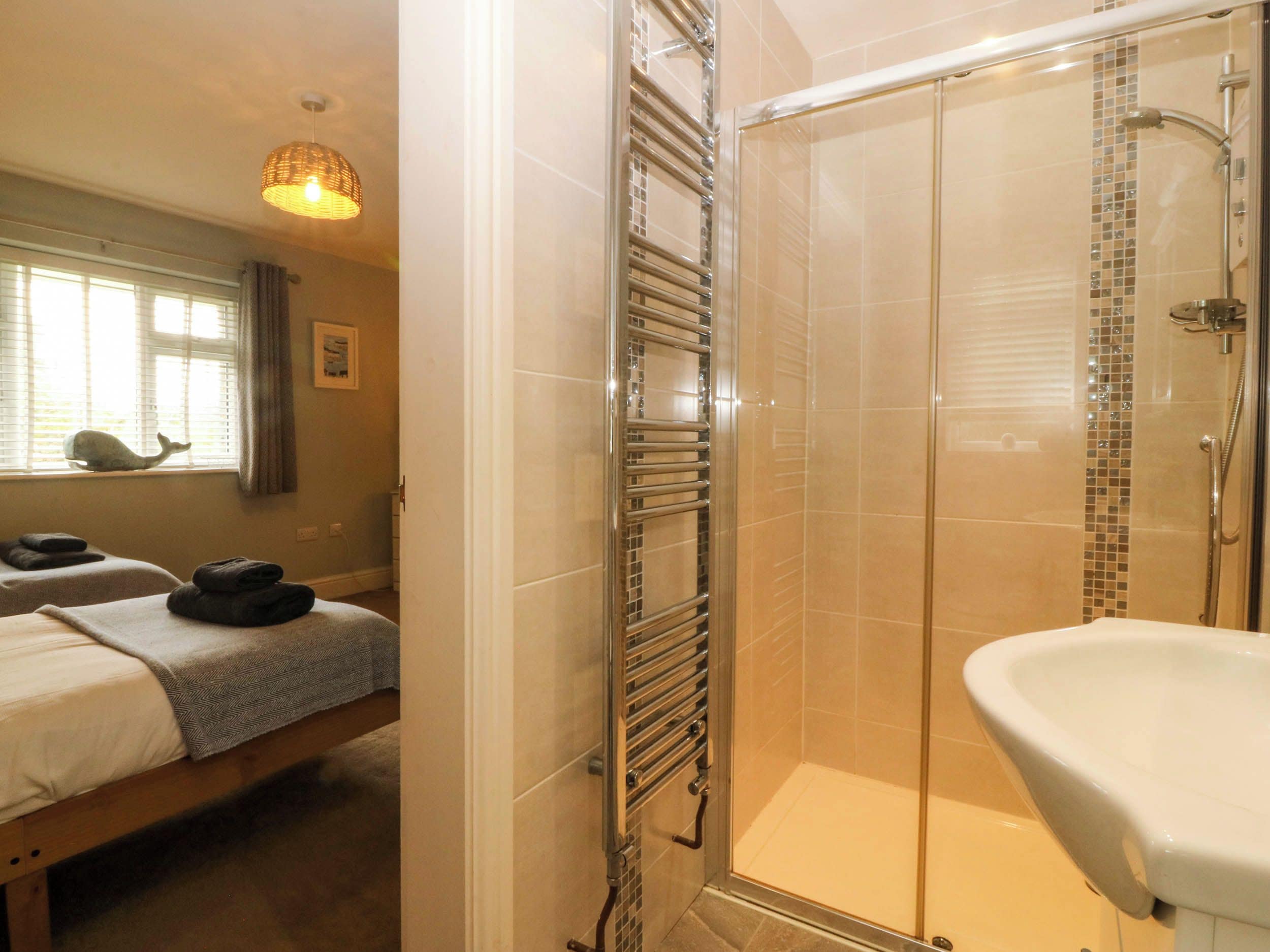 A bathroom with a shower, a sink, and a towel rack.