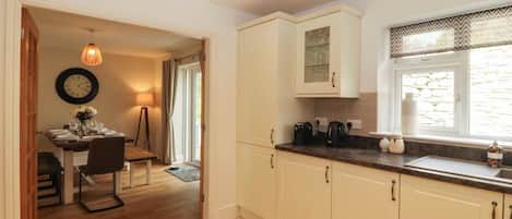 A kitchen with a dining area, a clock on the wall, and a window with a view.