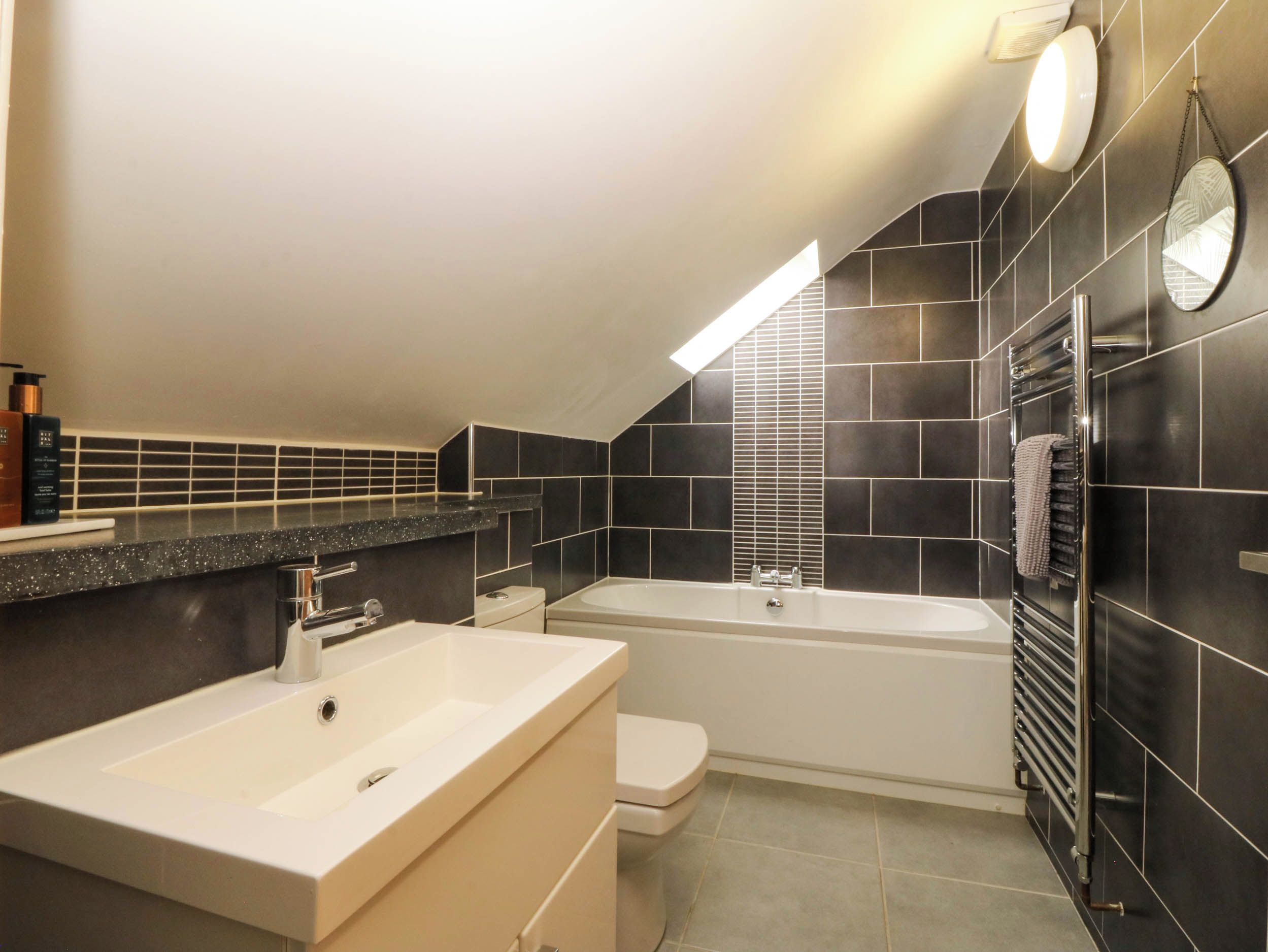 Een moderne badkamer met een bad, een toilet en een wastafelmeubel met een wastafel.
