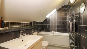 Een moderne badkamer met een bad, een toilet en een wastafelmeubel met een wastafel.