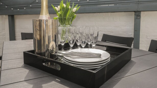 A table set with a champagne bottle, glasses, plates, and a vase of flowers. - 6 Sydney Road (Ramsgate)