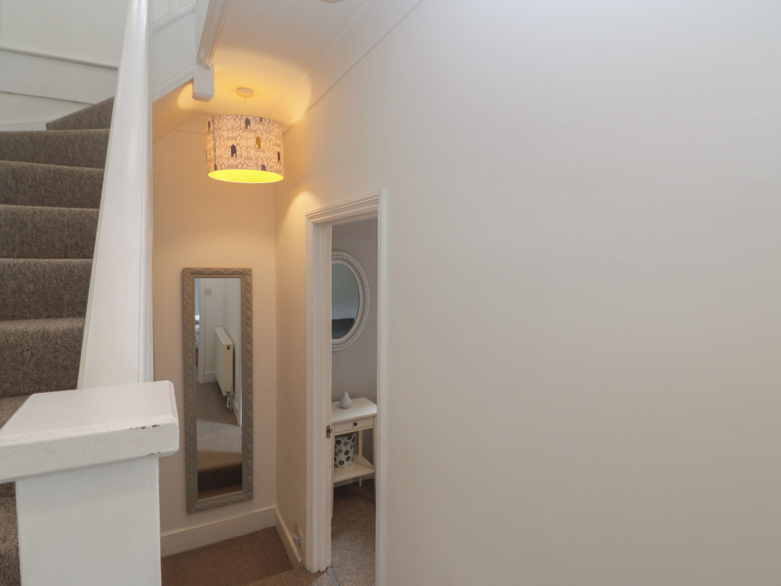 Een trap die leidt naar een kamer met een spiegel, een klein kaptafeltje en een lamp.
