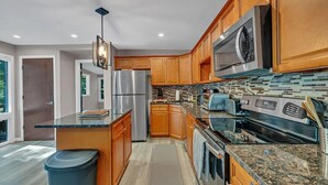 A modern kitchen with wooden cabinets, stainless steel appliances, and a granite countertop.