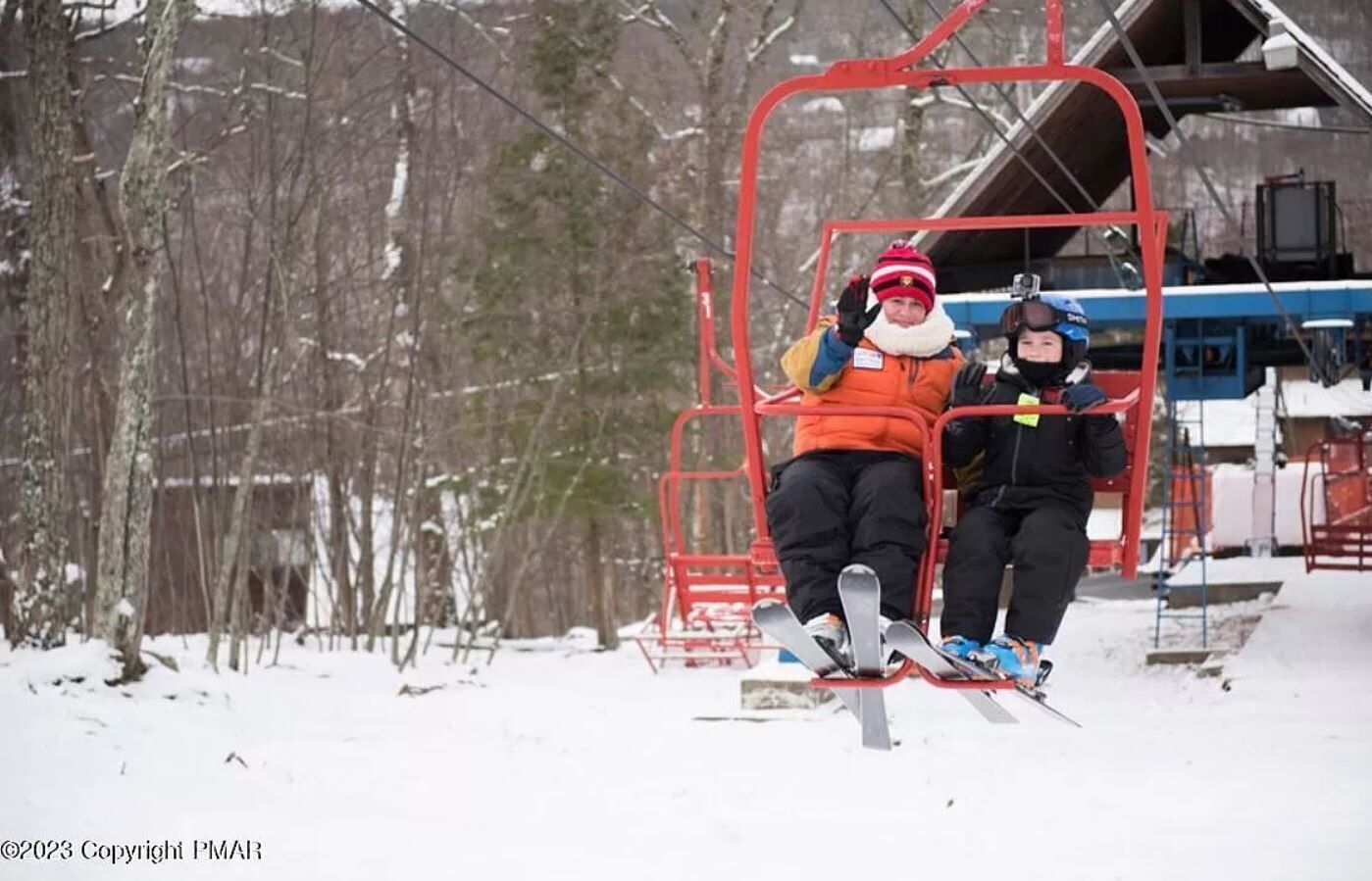 A ski lift with two skiers seated.