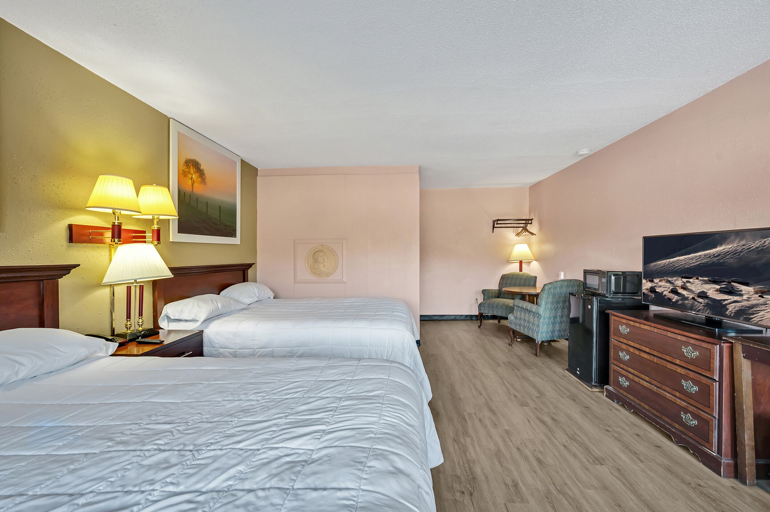 Habitación de hotel con dos camas, televisor, escritorio y silla.