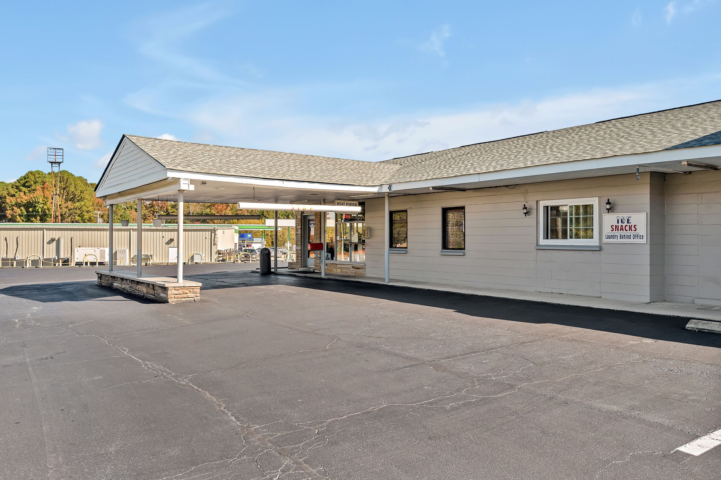 A building with a covered entrance, a sign for 'Ice Snacks Laundry Behind Office', and a parking lot.