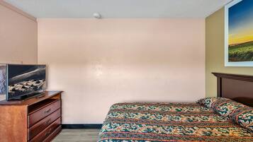 Een slaapkamer met een bed, een dressoir en een televisie op een standaard.
