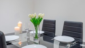 A dining table set with white plates, clear glasses, and a vase with white flowers. - Bermondsey London, 3 People Apartment, Peaceful (London)