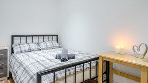A bedroom with a bed, bedside table, and a nightstand with candles. - Bermondsey London, 3 People Apartment, Peaceful (London)