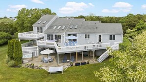 A two-story house with a covered patio, outdoor seating, and a hot tub. - Beach Getaway - Spacious Katama Beach House (Edgartown)