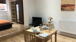 Un salon moderne comprenant un coin repas, un téléviseur et un tableau accroché au mur.