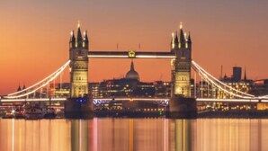 Une vue nocturne du Tower Bridge, avec le pont illuminé et la coupole de la cathédrale Saint-Paul en arrière-plan.