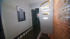 A staircase with a hand rankings poster and a modern light fixture. - Lux Stay near Patterson Park, John Hopkins, & Stadiums! Family & Pet-Friendly. (Baltimore)