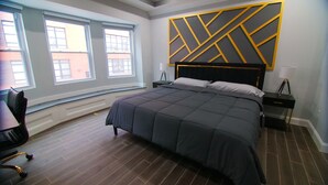 A modern bedroom with a large bed, a desk, and a chair. - Lux Stay near Patterson Park, John Hopkins, & Stadiums! Family & Pet-Friendly. (Baltimore)