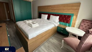 A modern hotel room with a wooden bed, teal wardrobe, and a pink armchair. - X SAPANCA OTEL (Sapanca)