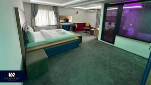 A modern hotel room with a bed, a desk, a red sofa, and a large window with curtains. - X SAPANCA OTEL (Sapanca)