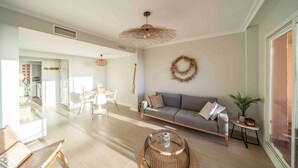 A modern living room with a sofa, coffee table, and a dining area with chairs and a table. - Casa Jsmina Calahonda With Seaview 2 bed 2 Bath (Sitio de Calahonda)